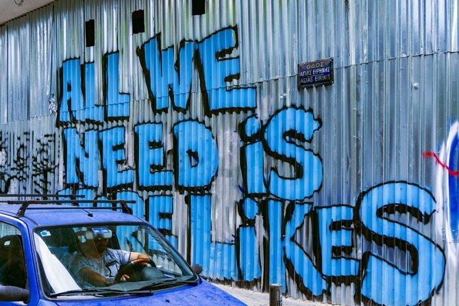 "Tek ihtiyacımız olan şey daha çok seviyor" yazan bir grafiti duvarının yanındaki araba